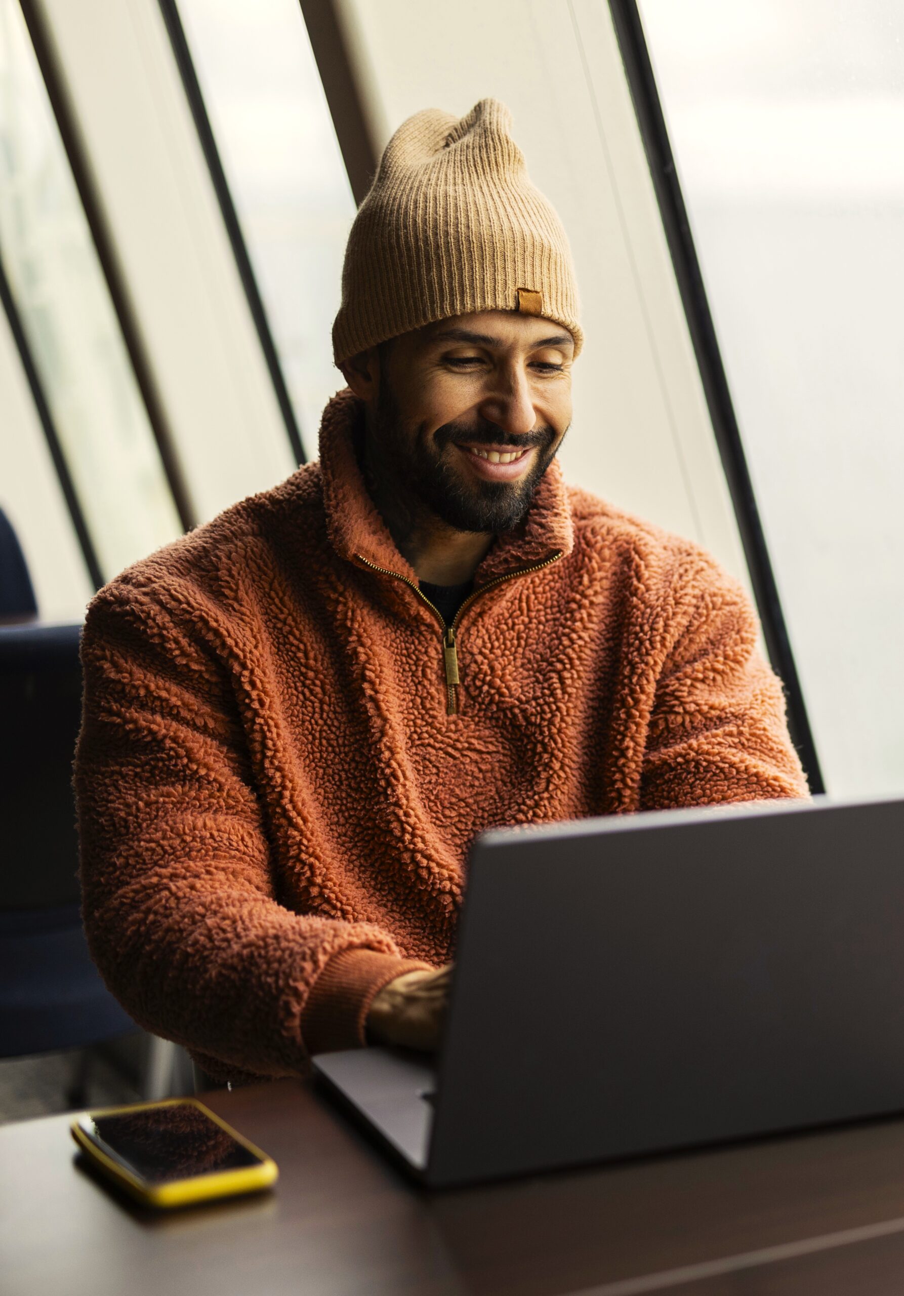 Content Marketer Smiling at Laptop in Coastal Office